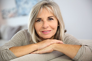 Smiling senior woman sitting in couch at home